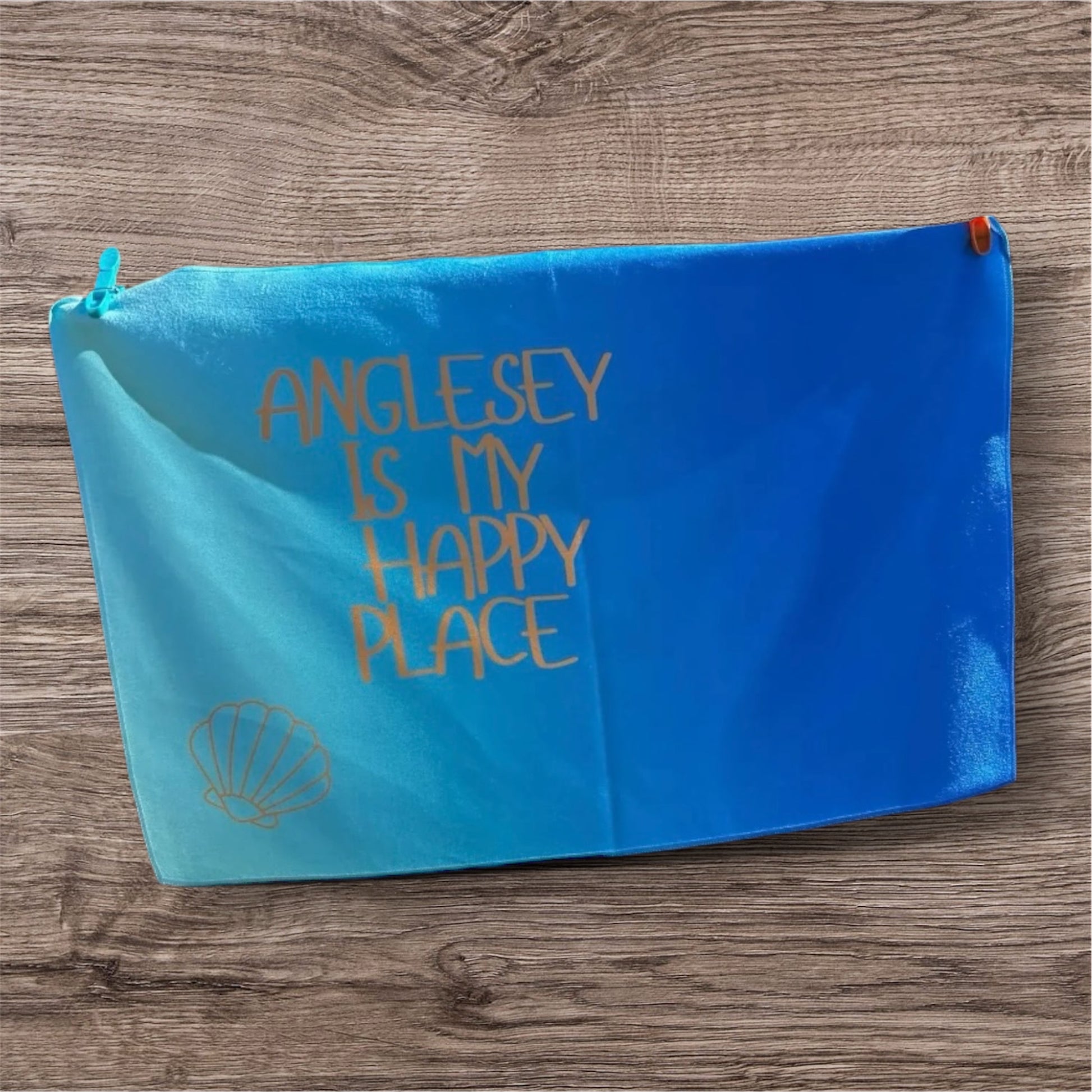 alt=“Quick-drying and absorbent microfibre tea towel with ‘Anglesey is my happy place’ slogan – ideal for beach lovers and coastal kitchens”