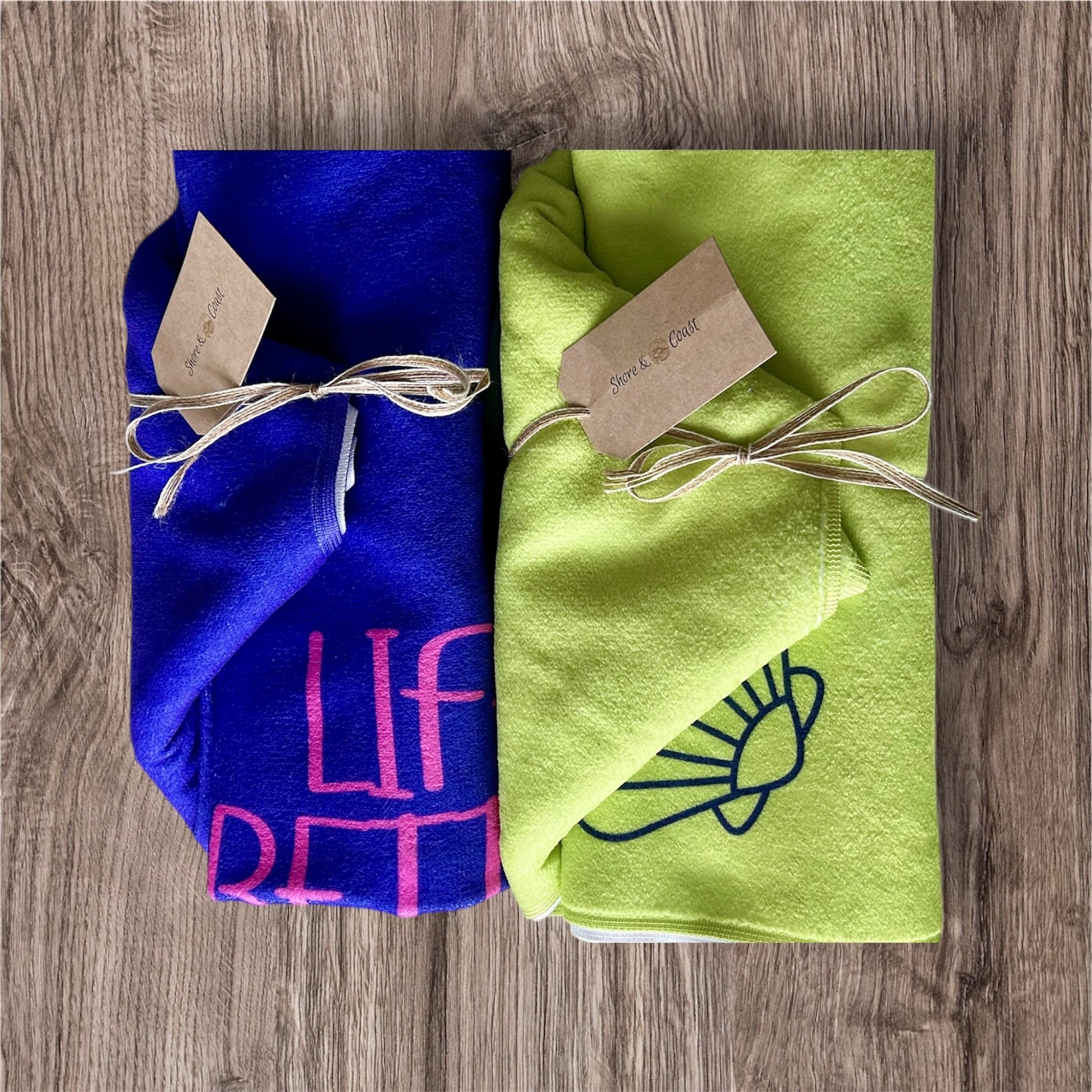 alt=“Lime green microfibre beach towel with cotton loops and the slogan ‘Life is better in Anglesey’ in bold yellow text – ultra-absorbent, quick-drying, and perfect for seaside adventures. Purple life is better in Anglesey with pink text