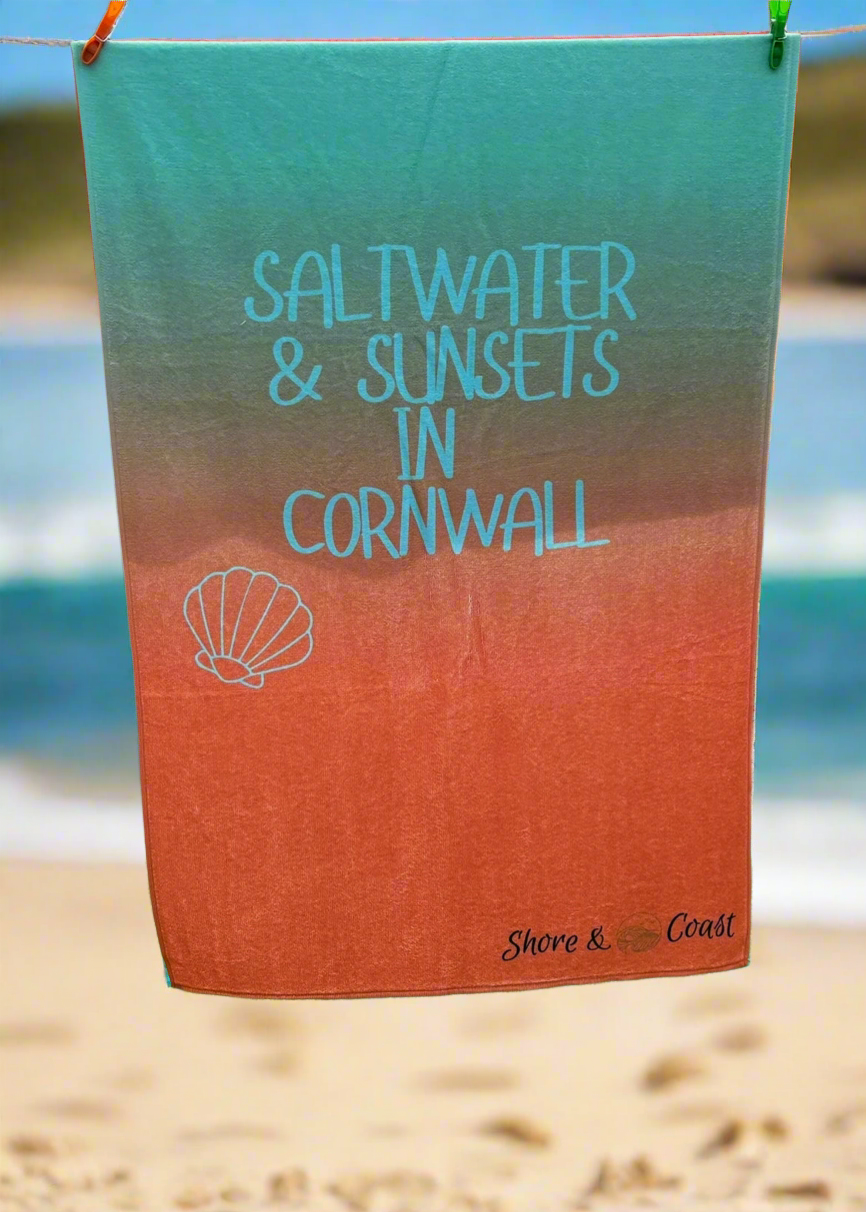 alt=“Lightweight, quick-drying mint and orange microfibre beach towel with the slogan ‘Saltwater & Sunsets in Cornwall’ in bold white text – perfect for beach days”