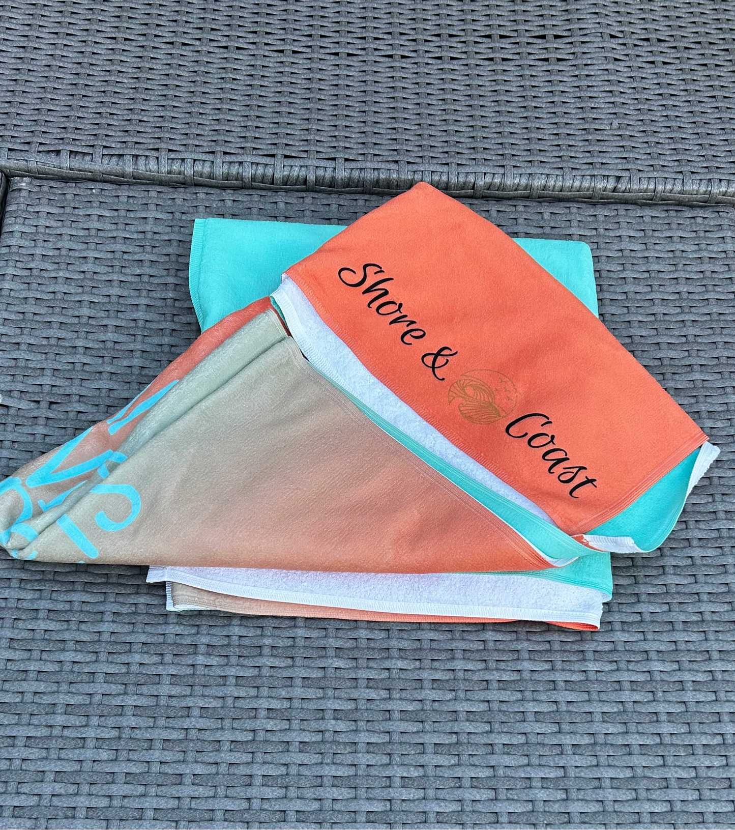 alt=“Mint and orange ombré microfibre beach towel with the slogan ‘Life is better in Anglesey’ in bold white text”