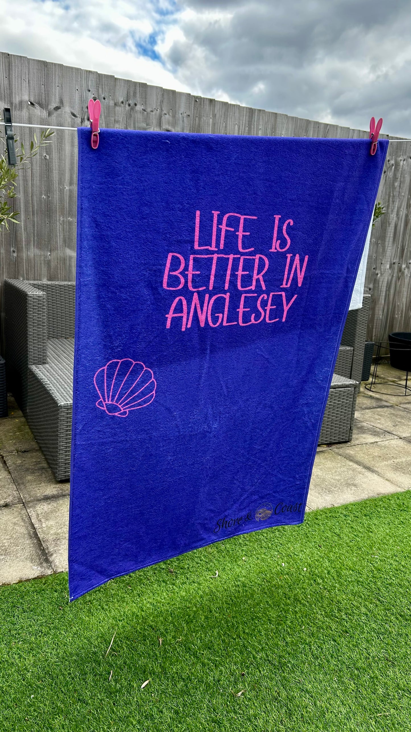 alt=“Purple microfibre beach towel with cotton loops and the slogan ‘Life is better in Anglesey’ in bold pink text – ultra-absorbent, quick-drying, and perfect for seaside adventures”