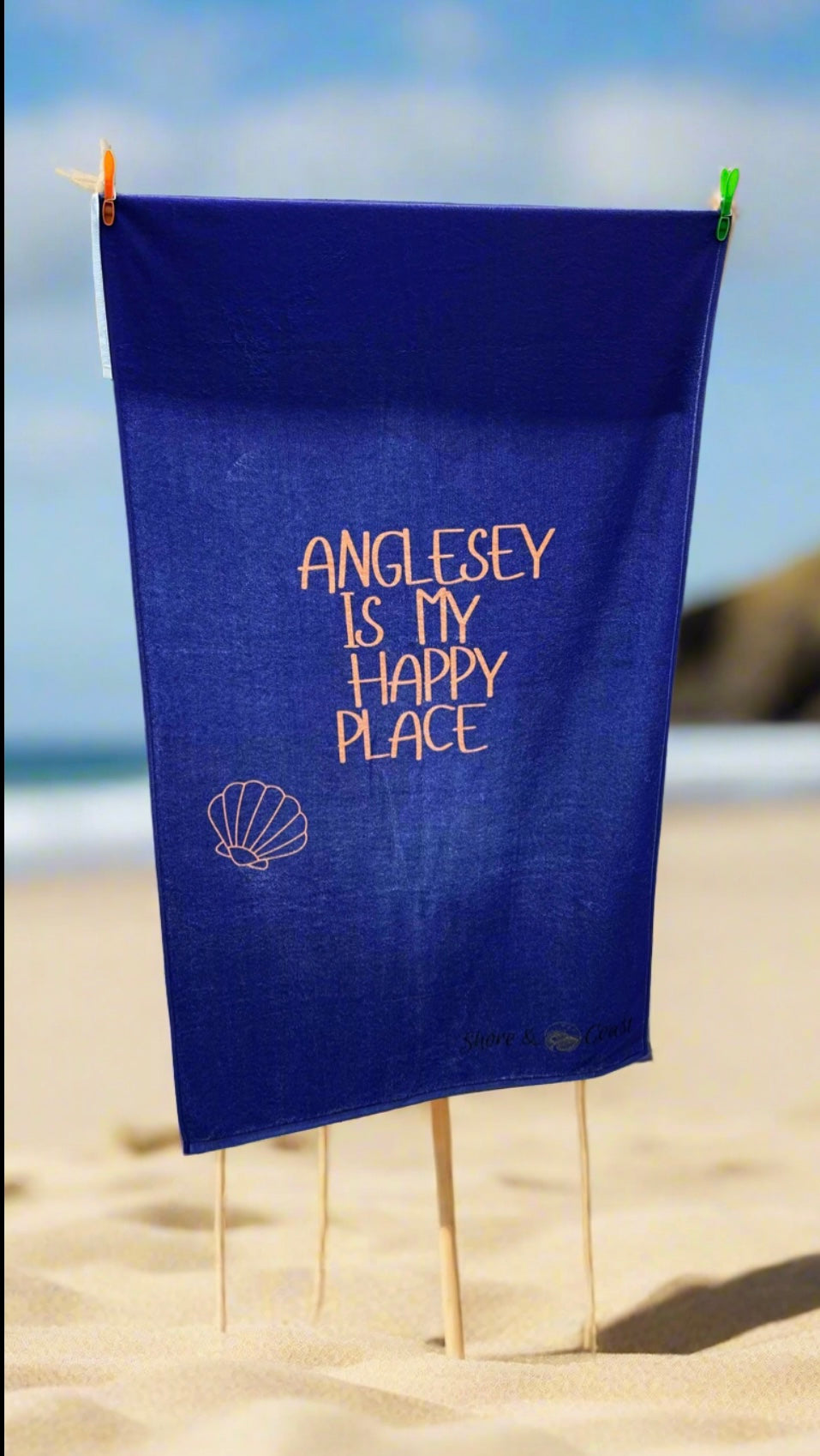 alt=“Navy microfibre beach towel with cotton loops featuring the slogan ‘Anglesey is my happy place’ in bold orange text – quick-drying, absorbent, and perfect for the coast”