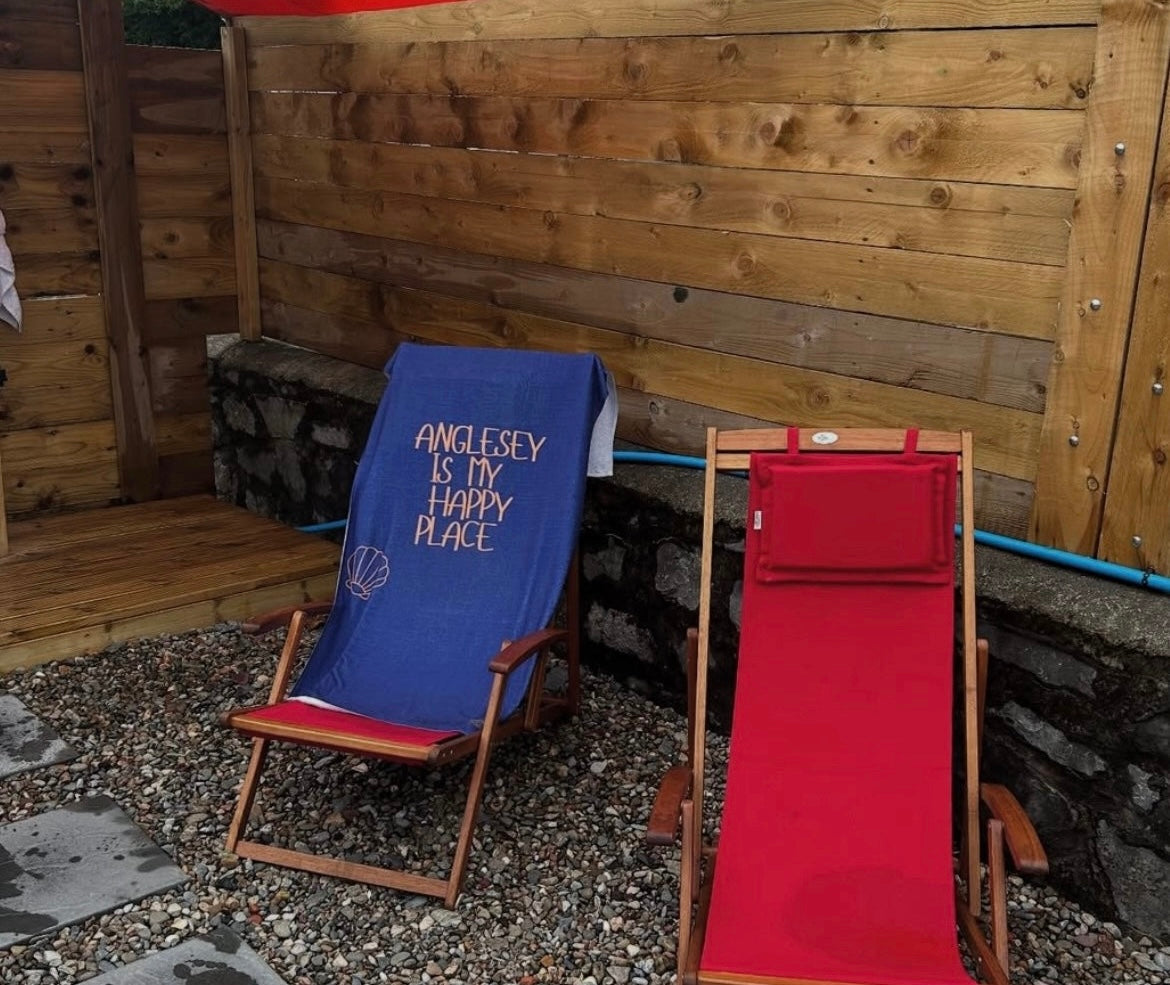 alt=“Navy microfibre beach towel with cotton loops featuring the slogan ‘Anglesey is my happy place’ in bold orange text – quick-drying, absorbent, and perfect for the coast”